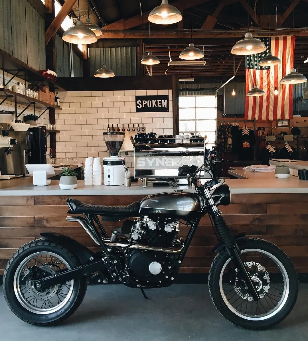 Coffee bar with an espresso machine and a custom motorcycle parked at the counter