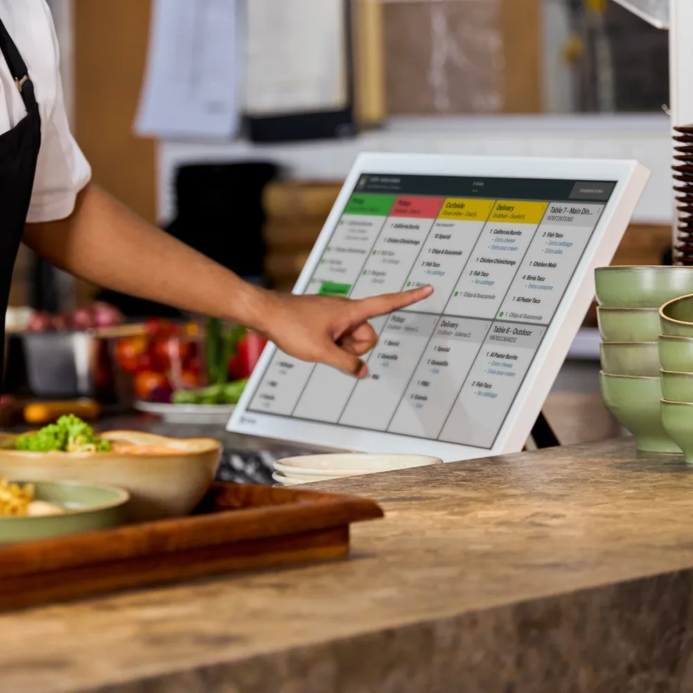 Restaurant staff tapping an order on a Clover Kitchen Display