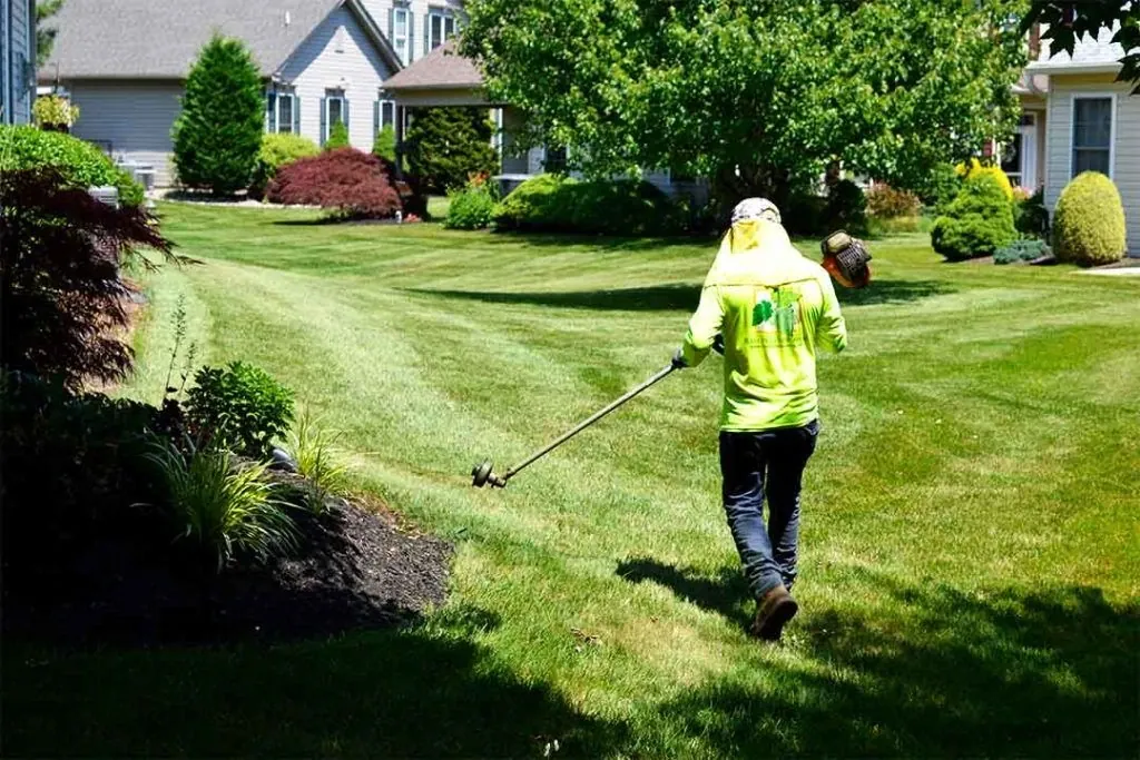 Landscaper trimming a lawn at a home